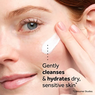 A close-up shows a womans face as she applies cream with her finger with the text Gently cleanses & hydrates dry, sensitive skin* *Consumer Studies.