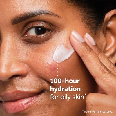 Close-up of a person applying cream to their cheek next to the text 100-hour hydration for oily skin * *Instrumental measures.