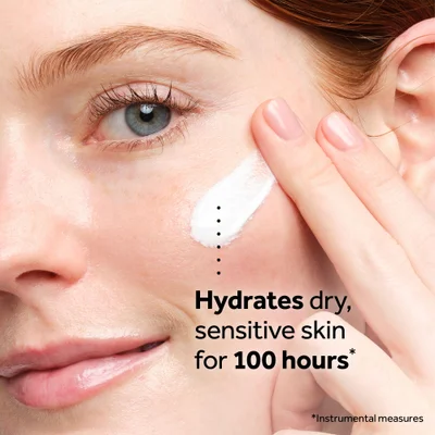 Close-up of a hand applying white cream to a persons face, with the text Hydrates dry sensitive skin for 100 hours* *Instrumental measures.
