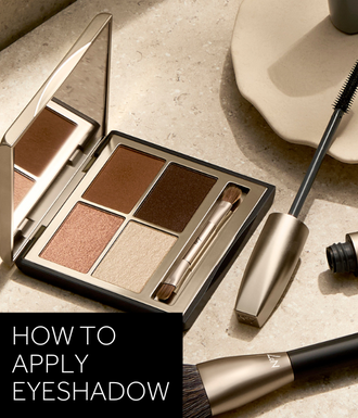'HOW TO APPLY EYESHADOW' text in white over black box. Image is photo of eyeshadow palette and mascara on beige background